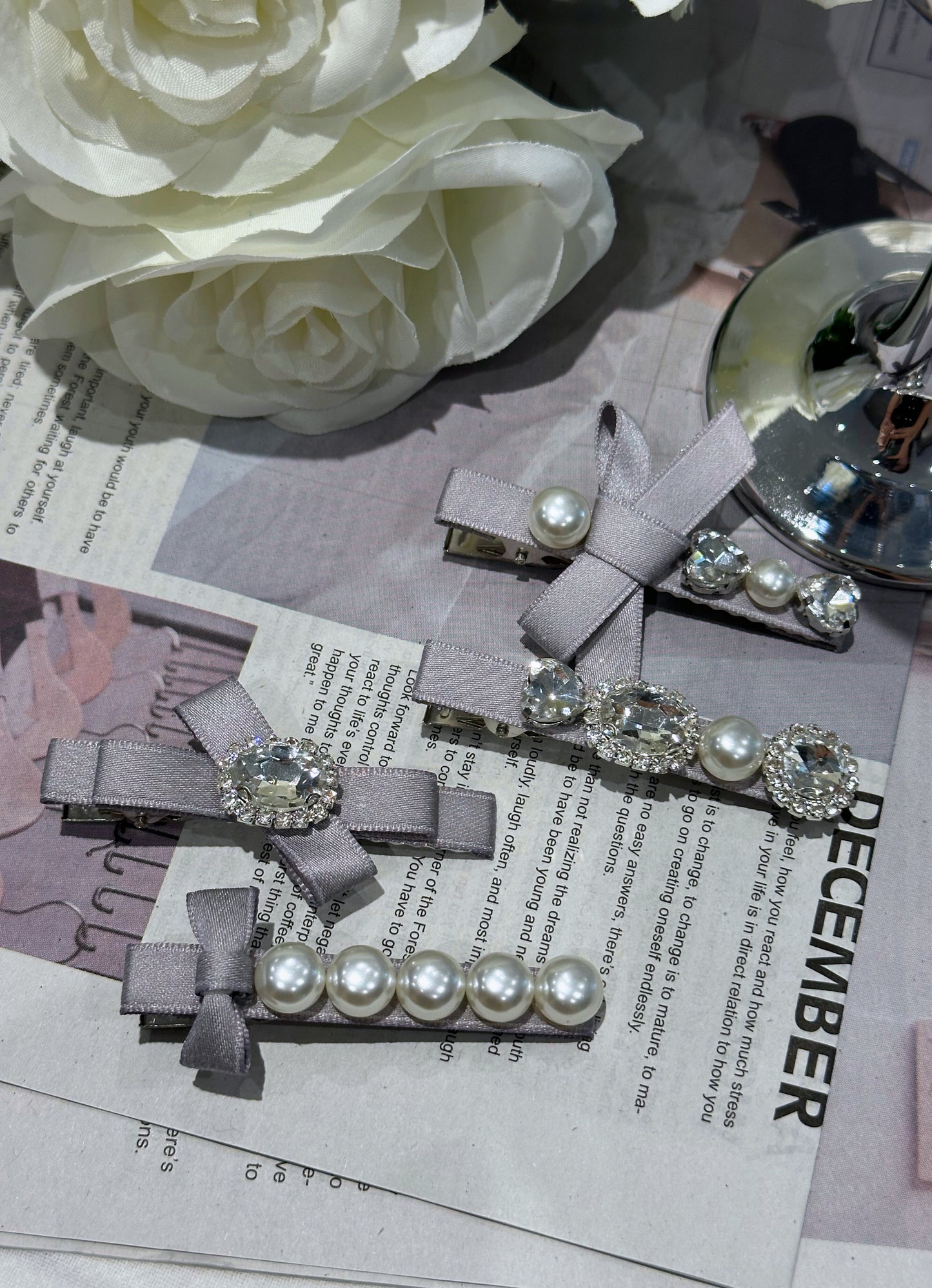 Set of ribbon bow hair clips with Swarovski crystals and pearls on a newspaper background