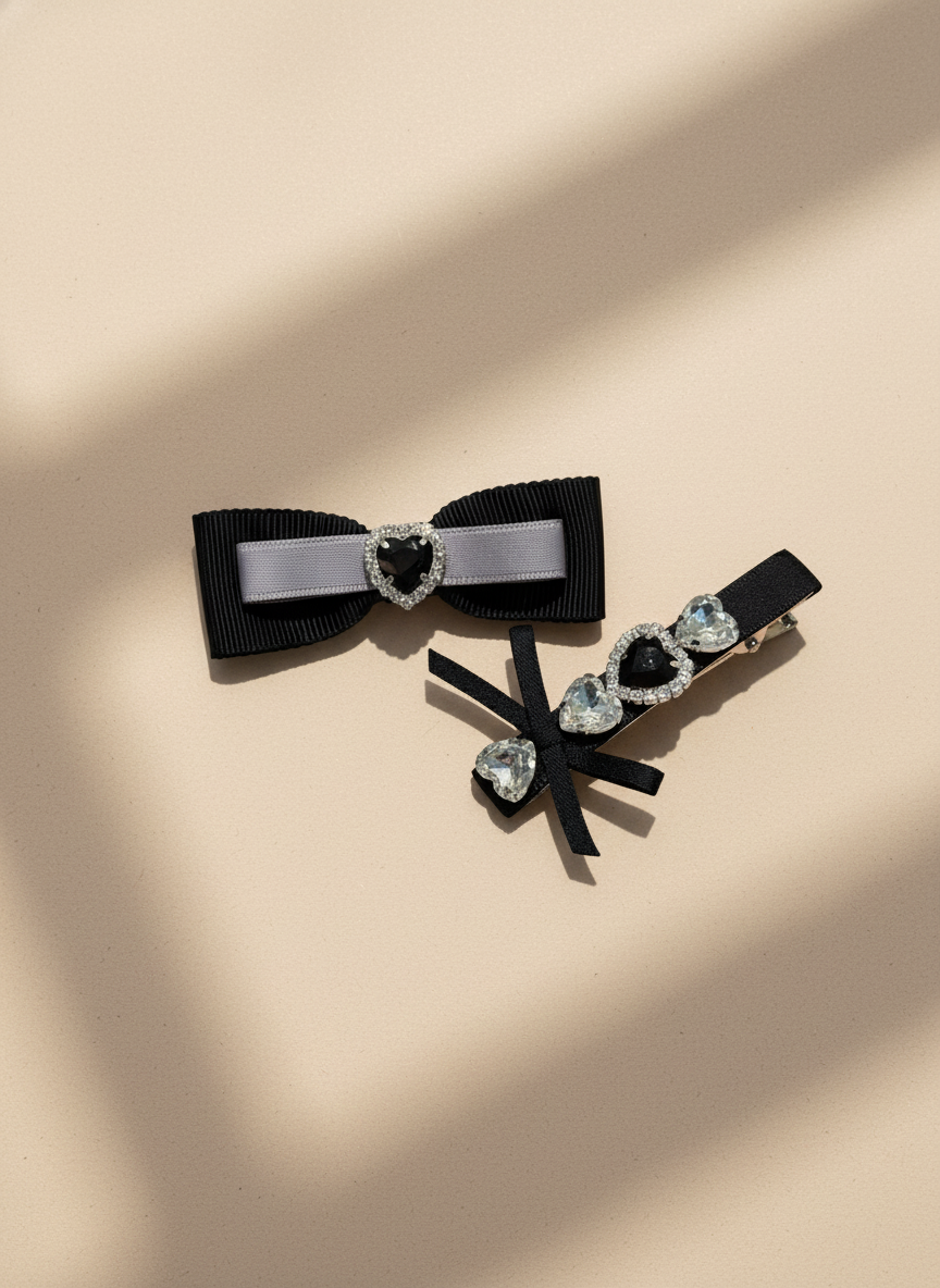 Two decorative black hair bows with heart-shaped Swarovski crystal centers hair clips/accessories on a beige background