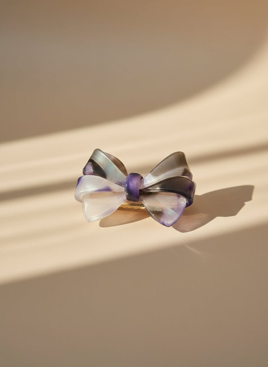 Purple and smoky ombré aztec bow hair clip with purple and gold accents on a beige background, only at petite murmure