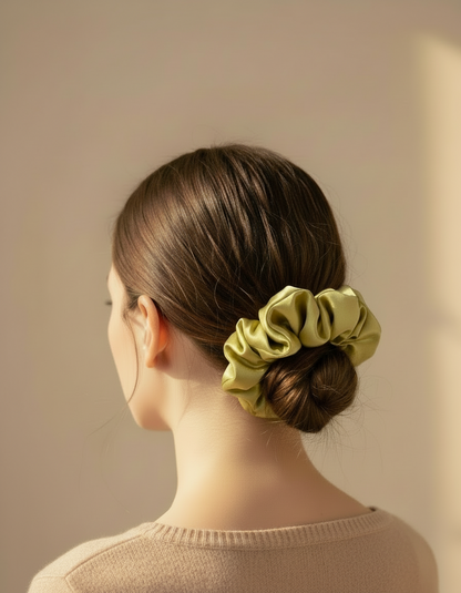 Woman with a Light champagne mustard handcrafted 30mm mulberry silk scrunchie  in her hair against a beige background