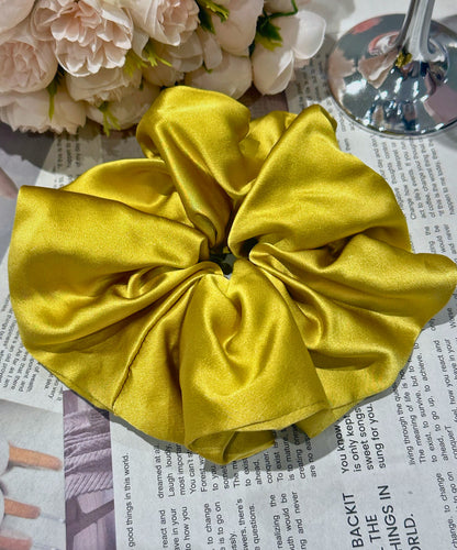 Mustard Yellow handcrafted 30mm mulberry silk scrunchie on a newspaper background