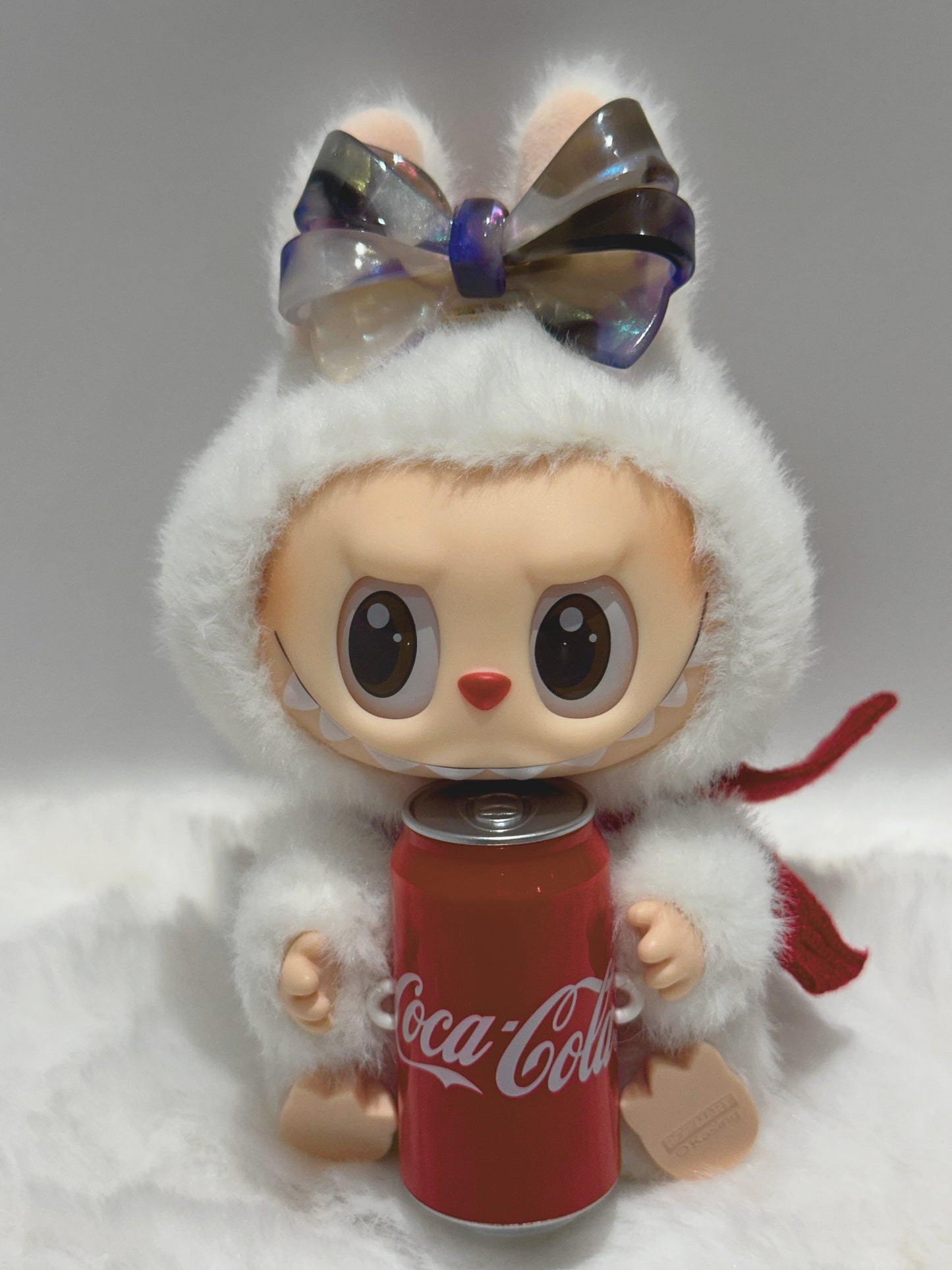 La BuBu  with Blush, purple, and smoky ombré aztec bow hair clip , holding a Coca-Cola can on a gray background