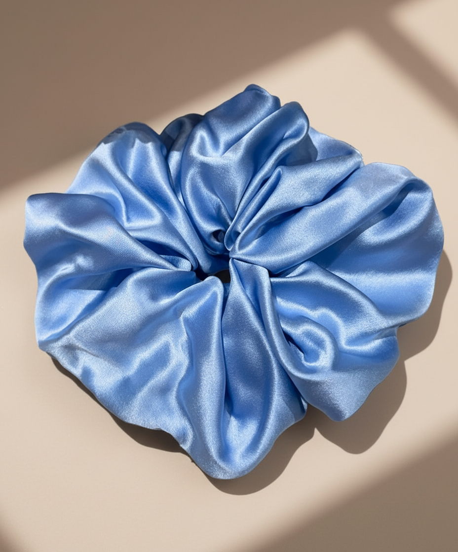 Blue handcrafted 30mm mulberry silk scrunchie on a beige background