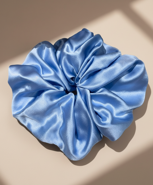 Blue handcrafted 30mm mulberry silk scrunchie on a beige background