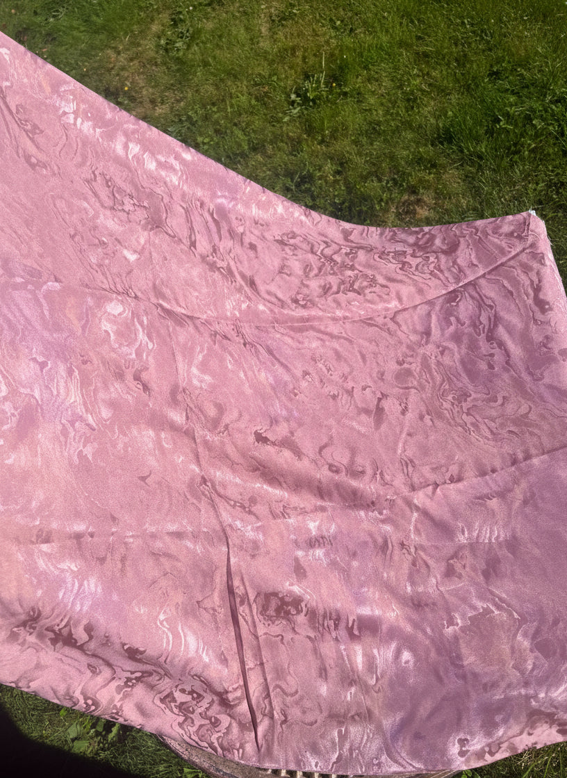 Pink rose aromatic scented ripply mulberry silk fabric draped over a green grassy area