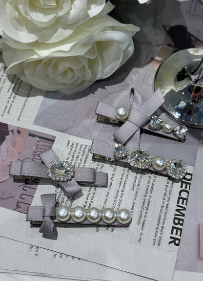 Set of ribbon bow hair clips with Swarovski crystals and pearls on a newspaper background