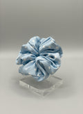 Babyblue handcrafted 30mm mulberry silk scrunchie with white polka dots on a clear stand against a gray background