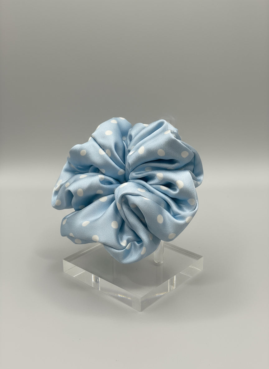 Babyblue handcrafted 30mm mulberry silk scrunchie with white polka dots on a clear stand against a gray background