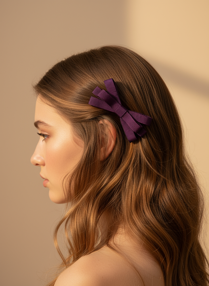 Woman with long brown hair wearing a purple hair clip against a beige background