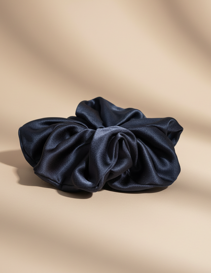 Navy handcrafted 30mm mulberry silk scrunchie on a beige background