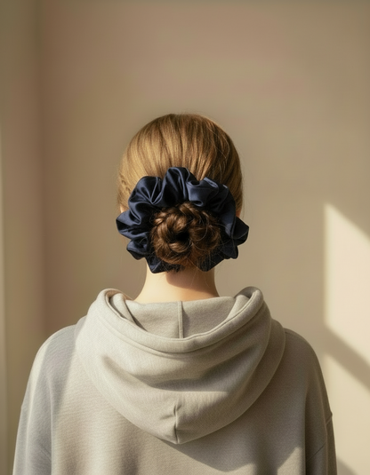Person wearing a gray hoodie with a Navy handcrafted 30mm mulberry silk scrunchie in their hair against a beige wall.