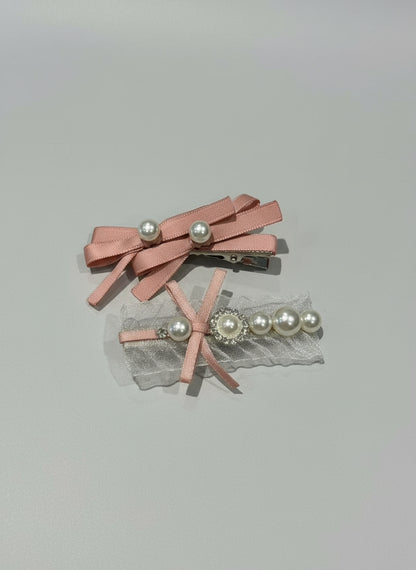 Two pink hair clips with ribbons , organza and pearls on a light gray background