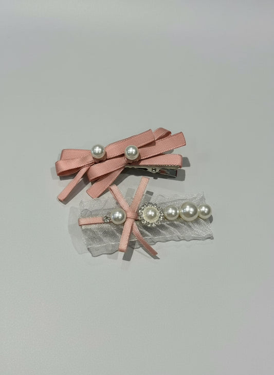 Two pink hair clips with ribbons , organza and pearls on a light gray background