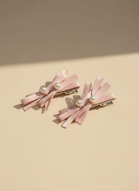 Two pink hair bows with layered bows and pearl centers on a beige background