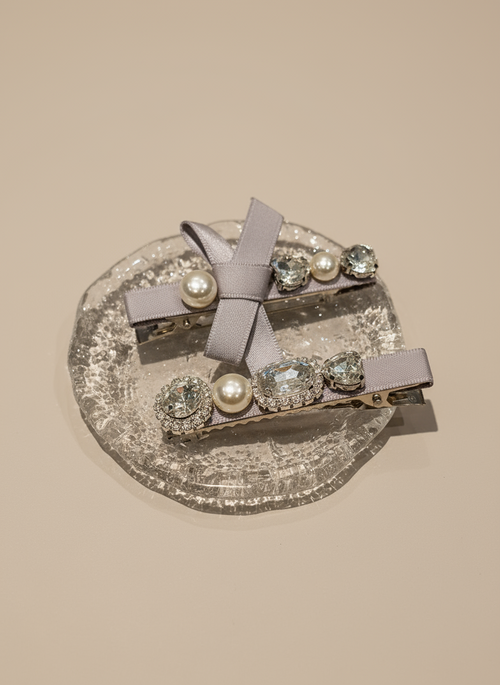 Set of decorative hair clips with bow, pearls and SWAROVSKI crystals on a glittery gray platform.