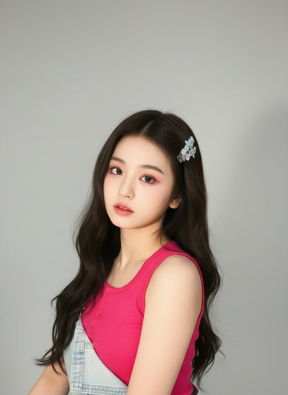 Woman with long dark hair wearing with set of greenish bow and Swarovski crystal hair clips in a pink top against a gray background, Kpop idol style