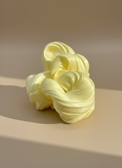 Cream yellow coloured hair  scrunchies on a beige background with soft lighting , only at petite murmure