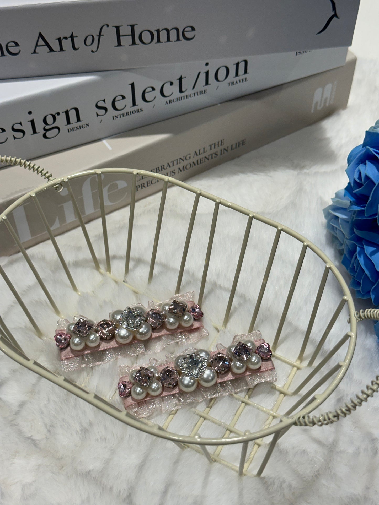 Pair of hair clips with Swarovski crystals and pearls embellished and silky organza  on a decorative stand with books and flowers in the background