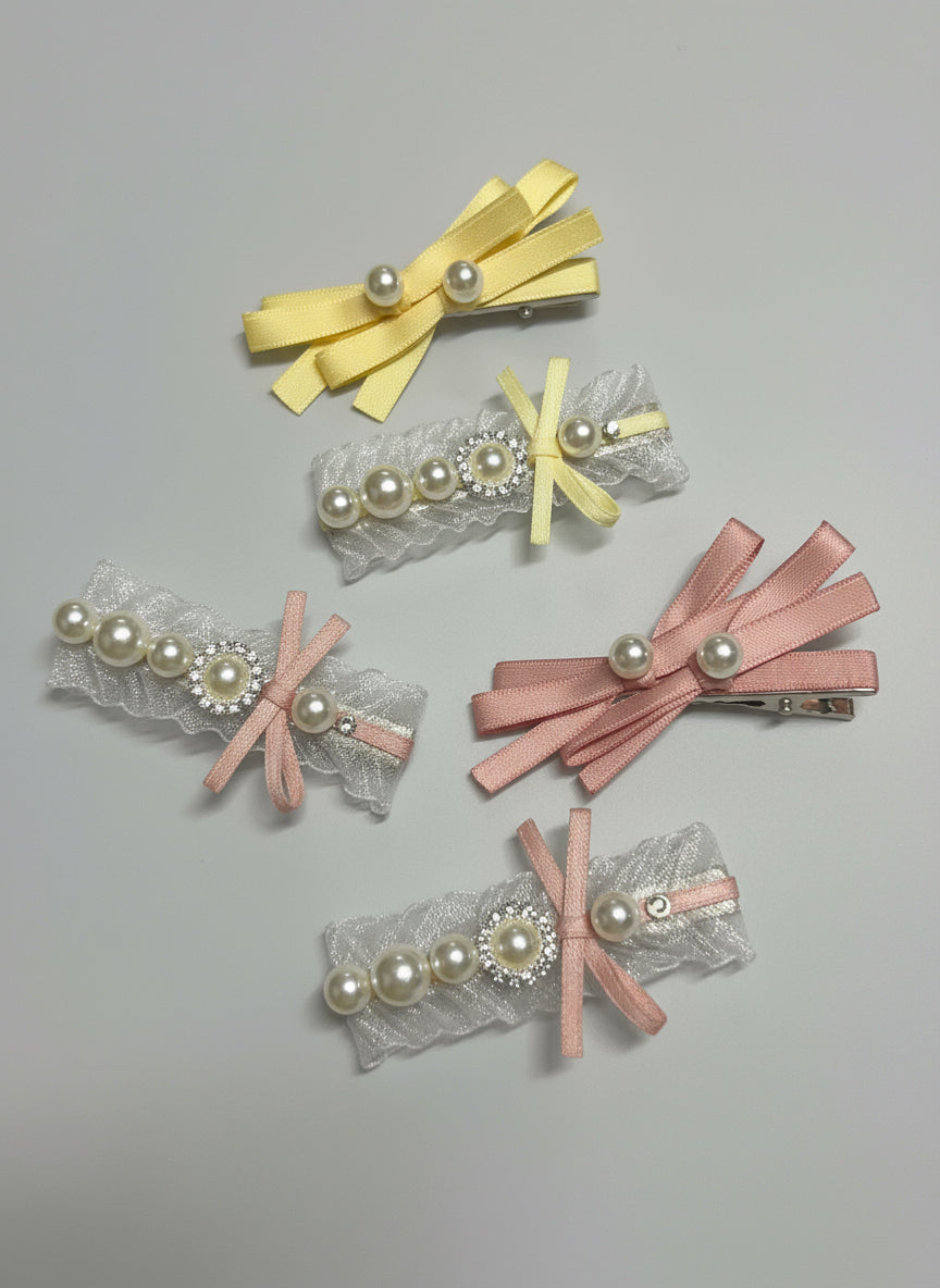 Set of five decorative hair clips with ribbons ,organza and pearls on a gray background