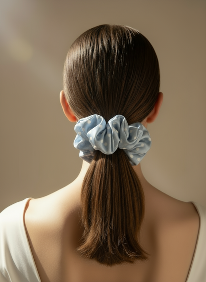 Person with a Babyblue handcrafted 30mm mulberry silk scrunchie with white polka dots in a low ponytail against a neutral background