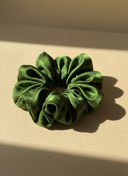 Green handmade ripply mulberry silk scrunchie with natural rose scented on a beige background