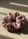 Pink handmade mulberry silk scrunchie with peony aroma scent scrunchie on a beige surface with soft shadows