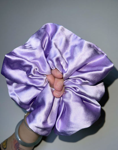 Lilac/ Lavender handcrafted 30mm mulberry silk scrunchie held by a hand against a gray background