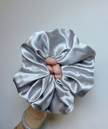 Silver Gray  handcrafted 30mm mulberry silk scrunchie held by a hand against a plain background