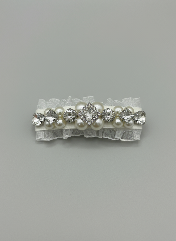 a white hair clip with Swarovski crystals and pearls embellished and silky organza  on a gray background. Only at Petite Murmure