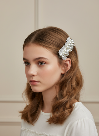 A young girl with a white hair clip with Swarovski crystals and pearls embellished and silky organza  on a neutral background. Only at Petite Murmure