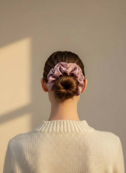 Person wearing a Pink handmade rose aromatic scented mulberry silk scrunchie in their hair against a beige wall