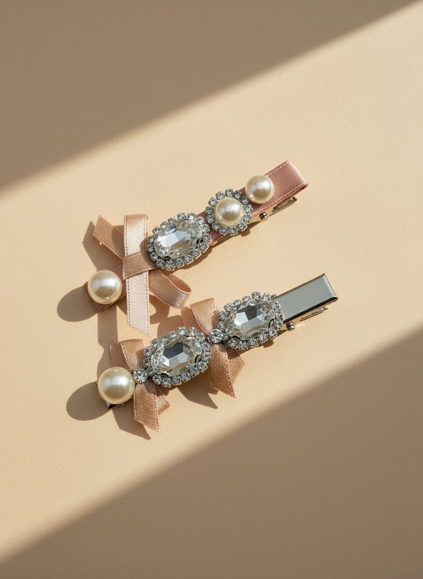 Two decorative bow hair clips with pearls and Swarovski crystals on a beige background