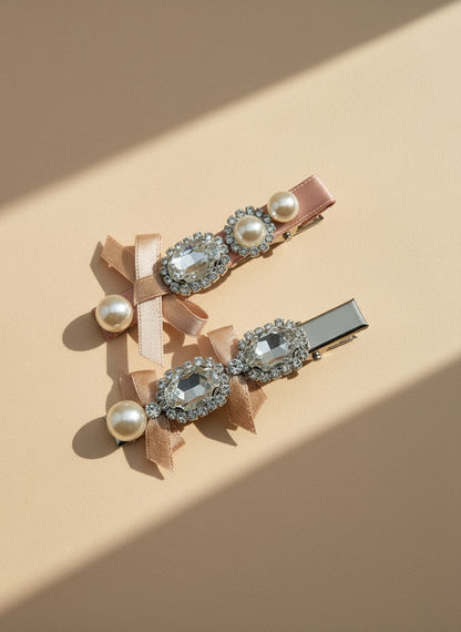 Two decorative bow hair clips with pearls and Swarovski crystals on a beige background