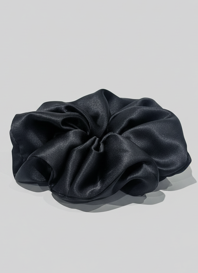 Black handcrafted 30mm mulberry silk scrunchie on a light gray background