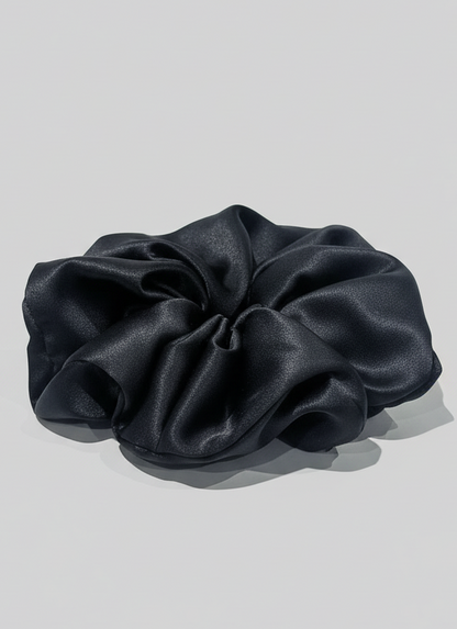 Black handcrafted 30mm mulberry silk scrunchie on a light gray background