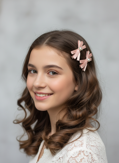 Young woman with styled hair featuring pink hair clips with layered bows and pearl centers against a plain background