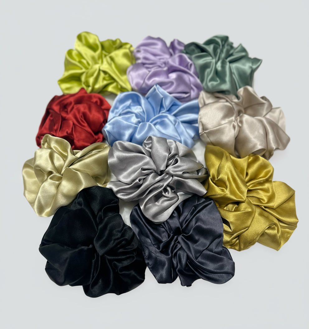 Collection of colorful handcrafted 30mm luminous mulberry silk scrunchies on a textured surface